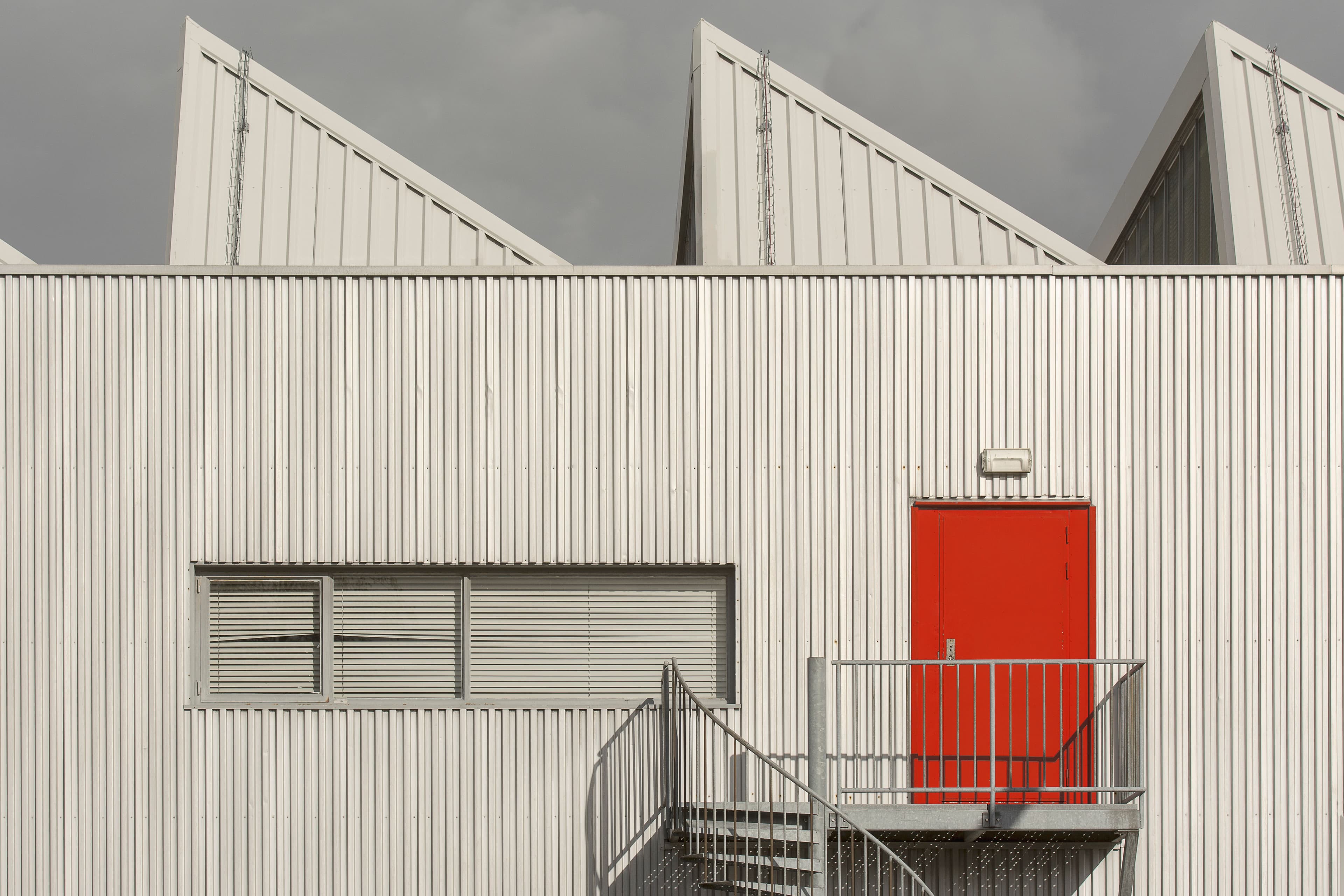 Commercial building exterior with a red service door.